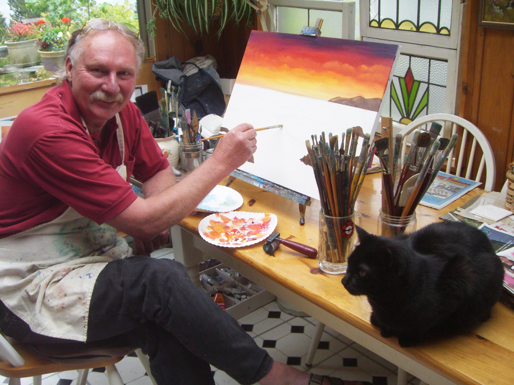 Larry Wall painting in Durland Ave Studio with his cat nearby